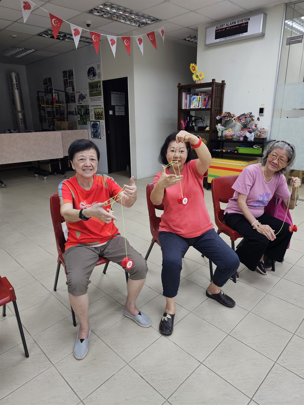 Three participants seated with their yoyos, smiling at the camera during a session